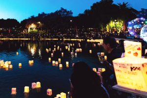 Paper lanterns float on a body of water at night.